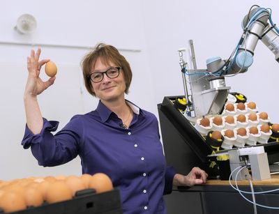 Endokrinologin Professorin Almuth Einspanier hält ein Ei in die Luft. Daneben ist ein Prototyp