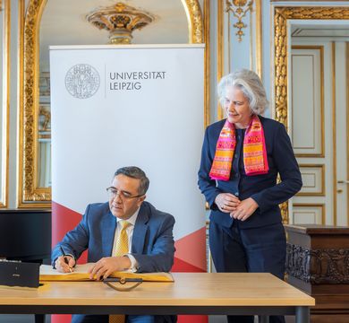 Der Botschafter Indiens in Deutschland, Ajit Vinayak Gupte, trug sich ins Goldene Buch der Alma mater ein. Neben ihm steht Rektorin Prof. Dr. Eva Inés Obergfell. Foto: Swen Reichhold Zu sehen ist sitzend und ins Goldene Buch der Uni Leipzig schreibend der Botschafter Indiens in Deutschland, Ajit Vinayak Gupte. Neben ihm steht Rektorin Prof. Dr. Eva Inés Obergfell. Foto: Swen Reichhold