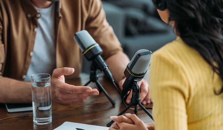 Zwei Menschen sitzen sich in einer Interviewsituation vor Mikrofonen gegenüber, Foto: colourbox.com