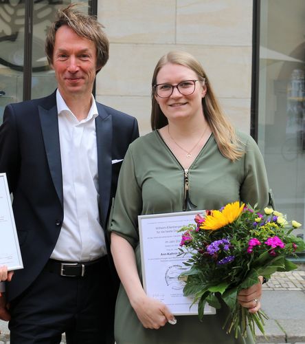 links Prof. Christoph Baums, rechts Ann-Kathrin Krieger mit Urkunde